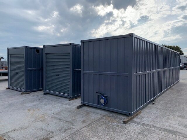 Finished enclosures in dark grey cladding staged for delivery