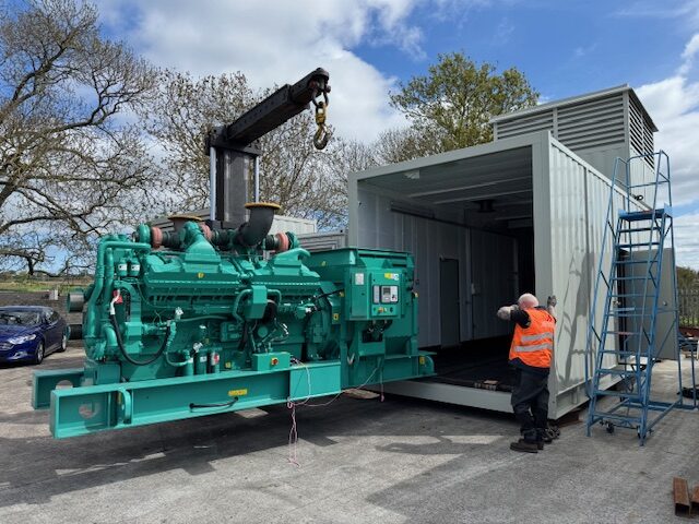 Crane lowering a generator set into an enclosure